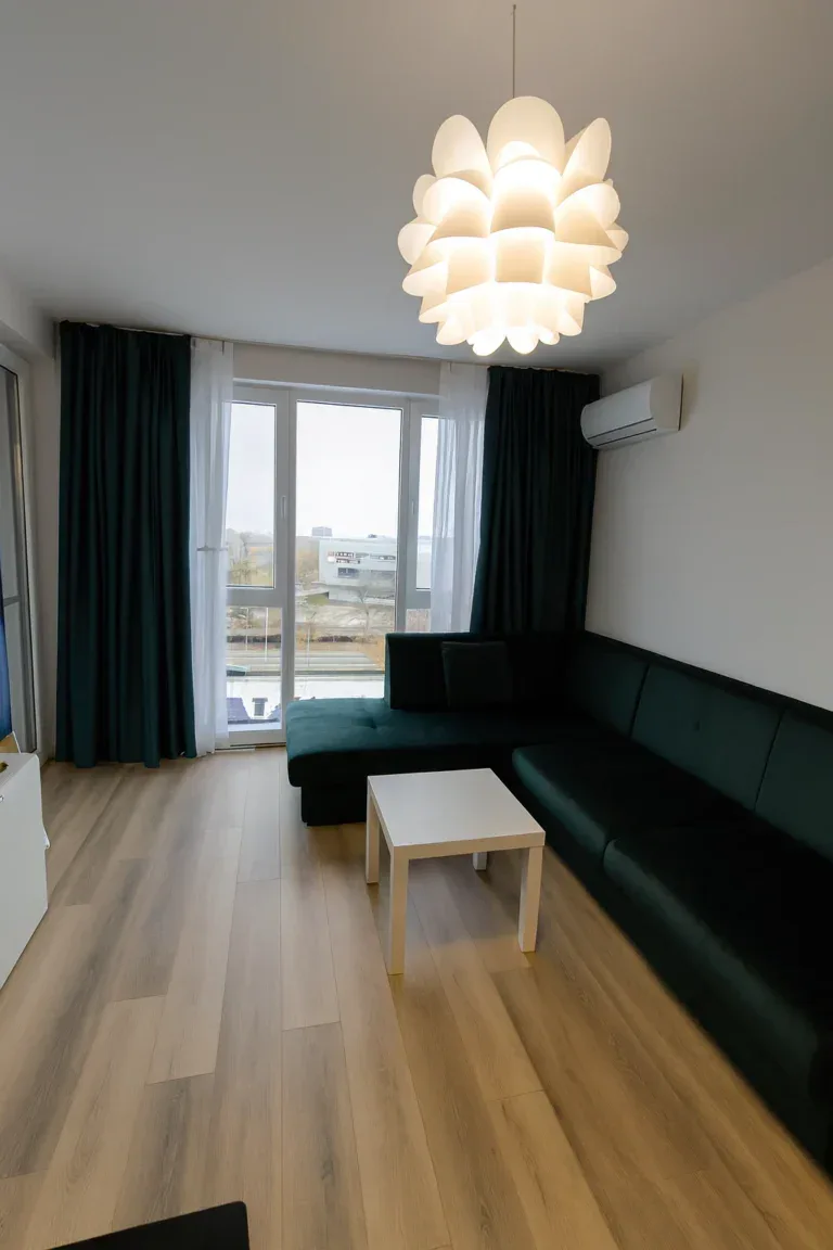 Хол с тъмнозелен диван и комбинация от плътни петролено зелени и бели ефирни пердета