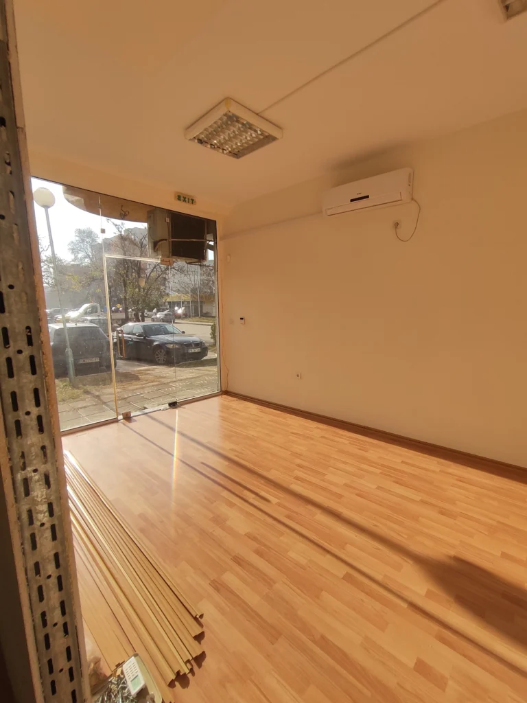 Празно помещение с дървен под и витрина, преди началото на обзавеждането