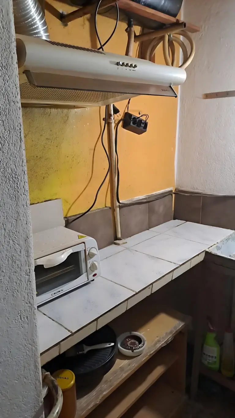 Стар кухненски ъгъл с жълти стени, абсорбатор и плочки