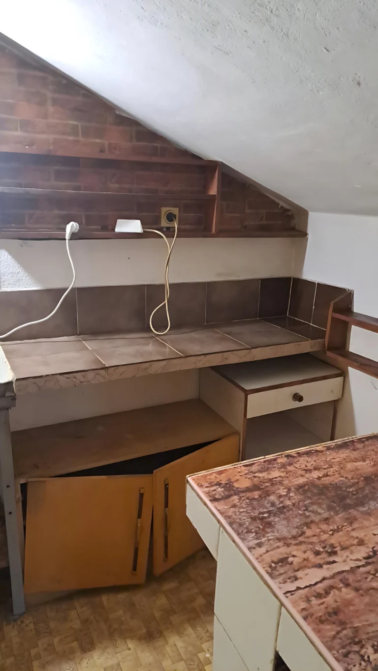 Стар плот под скосен таван; износени шкафове и бар