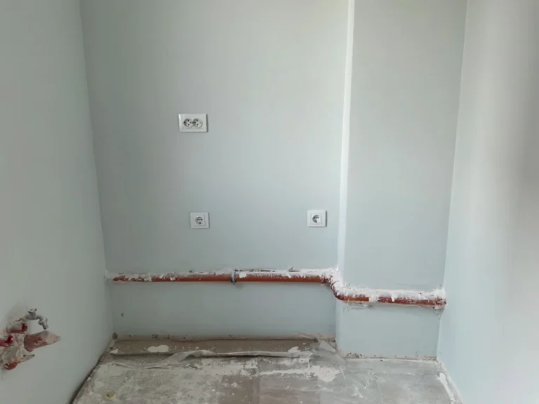 Празно кухненско пространство преди монтажа – неизмазани стени и открити тръби.